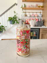 A 20oz glass beer can cup that has valentine designs around the cup in red, pink, yellow, and white. There is a heart shaped box of chocolates, champagne tower, bouquet of flowers, cherries, lockets, heart shaped cake, strawberries, bows, and flowers. The perfect galentine cup. 