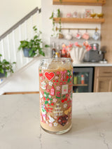 A 20oz glass beer can cup that has valentine designs around the cup in red, pink, yellow, and white. There is a heart shaped box of chocolates, champagne tower, bouquet of flowers, cherries, lockets, heart shaped cake, strawberries, bows, and flowers. The perfect galentine cup. 