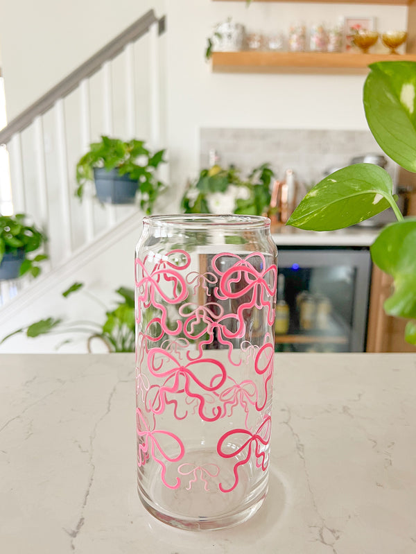 A cute 20oz glass coffee cup that is shaped like a beer can and has pink bows around the entire glass. Large pink bows are hot pink and small pink bows are light pink. Libbey beer can glass cup. 