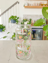 A cute 20oz libbey beer can glass coffee cup that is shaped like a beer can and has swans in water, lemons, oranges on branches, pink bows, and florals in a repeating pattern around the glass. 