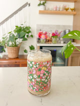 A cute 16oz glass coffee cup that is shaped like a beer can and has lemons, pink and white flowers, bows, butterflies, and little strawberries in a colorful repeating pattern around the glass. 