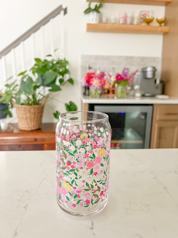 A cute 16oz glass coffee cup that is shaped like a beer can and has lemons, pink and white flowers, bows, butterflies, and little strawberries in a colorful repeating pattern around the glass. 