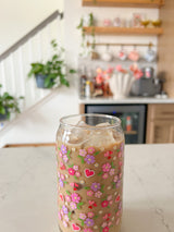 A cute 16oz glass coffee cup that is shaped like a beer can and has purple, pink and hot pink hearts all over the glass with red hearts with doilies around them. The perfect subtle valentine glass or galentine glass. 