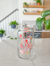 A cute 16oz glass coffee cup that is shaped like a beer can and has a design on the front of the glass that say "XO OX XO" and has florals and butterflies with heart wings around the letters. The colors are hot pink, light pink and pops of yellow and white. 