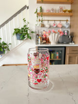 A cute 16oz glass coffee cup that is shaped like a beer can and has valentine designs around the cup in red, pink, yellow, and white. There is a heart shaped box of chocolates, champagne tower, bouquet of flowers, cherries, lockets, heart shaped cake, strawberries, bows, and flowers. The perfect galentine cup. 