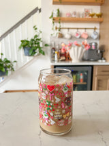 A cute 16oz glass coffee cup that is shaped like a beer can and has valentine designs around the cup in red, pink, yellow, and white. There is a heart shaped box of chocolates, champagne tower, bouquet of flowers, cherries, lockets, heart shaped cake, strawberries, bows, and flowers. The perfect galentine cup. 