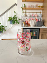 A cute 16oz glass coffee cup that is shaped like a beer can and has valentine designs around the cup in red, pink, yellow, and white. There is a heart shaped box of chocolates, champagne tower, bouquet of flowers, cherries, lockets, heart shaped cake, strawberries, bows, and flowers. The perfect galentine cup. 