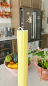 This is a taper candle that is yellow lemon in color and has a ribbed pattern on it. 