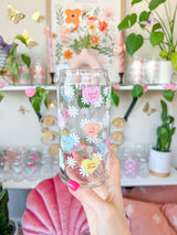 A cute 20oz glass coffee cup that is shaped like a beer can and has different colored candy hearts all over the glass with white daisies. Hearts are yellow, blue, pink, green, and orange and say cute drinks inside the heart.