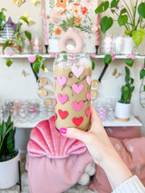 A cute libbey 20oz can glass coffee cup that is shaped like a beer can and has different shade of pink hearts around the glass. 