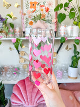 A cute libbey 20oz can glass coffee cup that is shaped like a beer can and has different shade of pink hearts around the glass. 