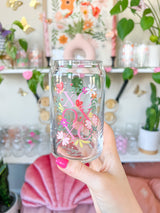 A cute 16oz glass coffee cup that is shaped like a beer can and has a design on the front of the glass that say "XO OX XO" and has florals and butterflies with heart wings around the letters. The colors are hot pink, light pink and pops of yellow and white. 